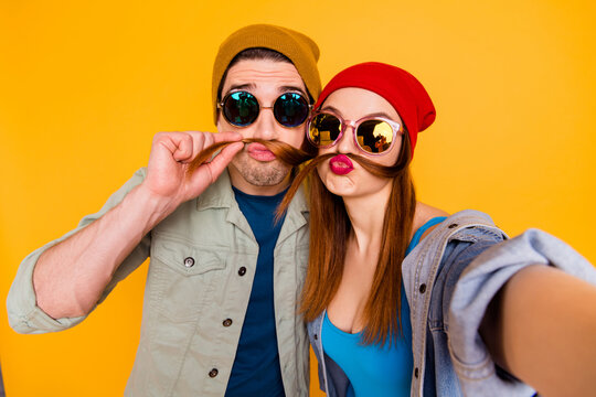 Self-portrait of his he her she nice attractive childish humorous cheerful couple spending weekend making fake moustache having fun isolated on bright vivid shine vibrant yellow color background