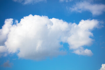 Naklejka na ściany i meble Blue sky with a fluffy white cloud.