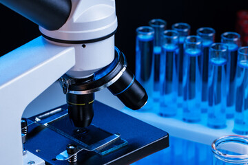 Close up of laboratory microscope with set of test tubes with blue liquid