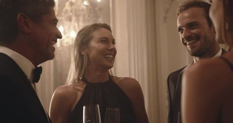 Group of friends having a discussion over a few drinks. High society people talking and having a good time together at a party.
