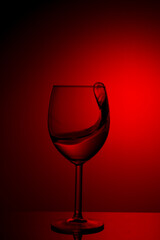 Plakat A splash of red wine in a glass on a red background