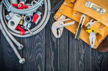 Set of tools in the bag and spare parts for plumbers on dark vintage wooden boards