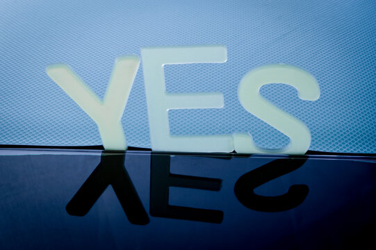 The word Yes written in plastic letters on a black mirroring surface. Business, motivation and education concept.