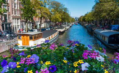 Fototapeta na wymiar Gracht Canal in amsterdam netherlands with boats and flowers on a bridge