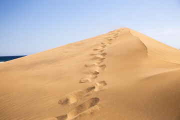 Fototapeta na wymiar footsteps on sand dune against clear blue sky in Maspalomas, Gran Canaria