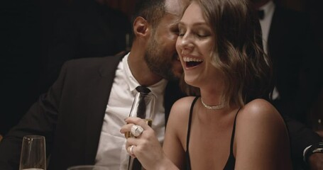 Man whispering something funny to a woman at dinner. Couple enjoying together at gala party, smiling and toasting wine.
- Powered by Adobe