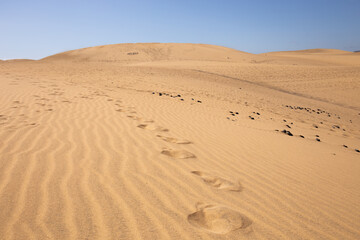 footsteps on sand dunes against clear blue sky in Maspalomas, Gran Canaria
