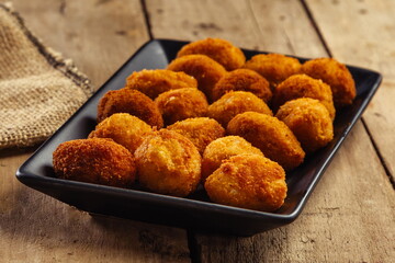 Croquettes in black plate on wooden table
