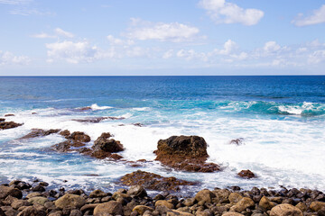 Fototapeta na wymiar Atlantic ocean with waves and rocks against blue sky with clouds in Agaete, Las Palmas