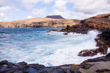 Atlantic ocean with waves and rocks against blue sky with clouds in Agaete, Las Palmas