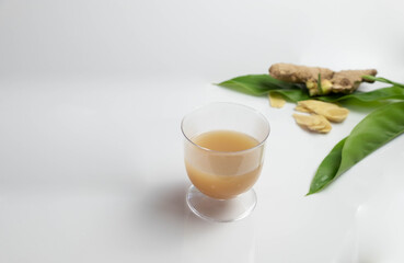 Hot ginger in a glass With fresh ginger and leaves on the sackcloth floor
