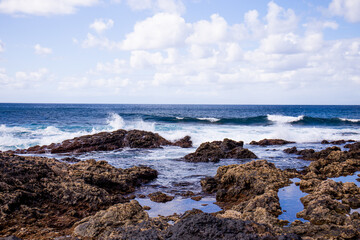 Fototapeta na wymiar Atlantic ocean with waves and rocks against blue sky with clouds in Agaete, Las Palmas