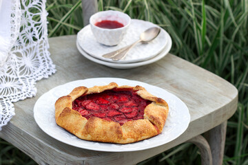 Whole grain flour cake stuffed with strawberries with honey sauce on a chair in the garden. Rustic style.