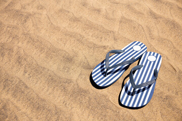 Fototapeta na wymiar striped flip flops on sand at sunny day in Maspalomas, Gran Canaria