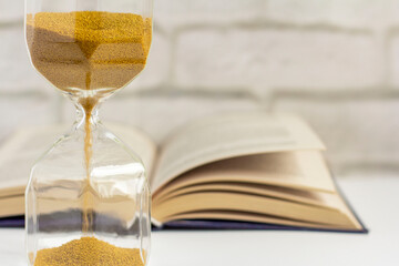 An hourglass and an open book on the table.