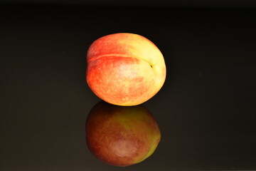 Ripe juicy organic nectarine, macro, on a black background.