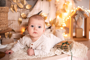 Fototapeta premium A small baby in light clothing lies on the background of the Christmas decor.