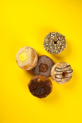 Assorted and colourful gourmet doughnuts on a vibrant yellow background