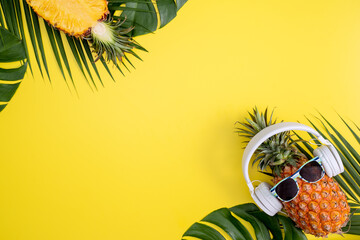 Funny pineapple wearing white headphone, listen music, isolated on yellow background with tropical...