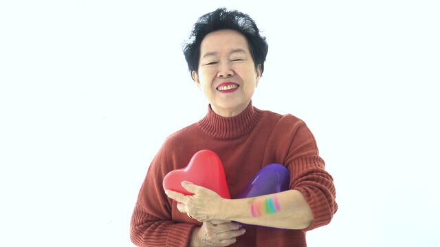 Asian elder mother support LGTBQ children thumb up smile with purple red balloon heart rainbow pride paint