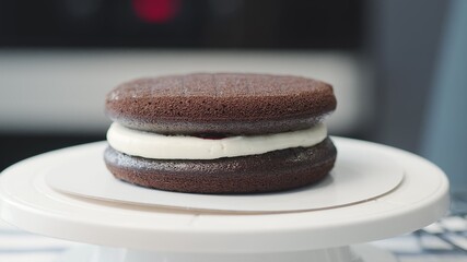 Cooking cake at home. Two levels on chocolate cake with white cream and cherry jam in between