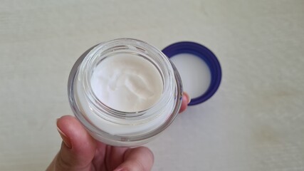 hand holding an open can with moisturizing cream