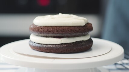 Cooking cake at home. Two levels on chocolate cake with white cream and cherry jam in between and on top