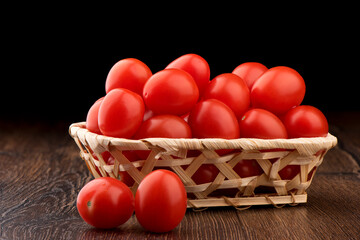 Red cherry tomatoes in a wooden basket.