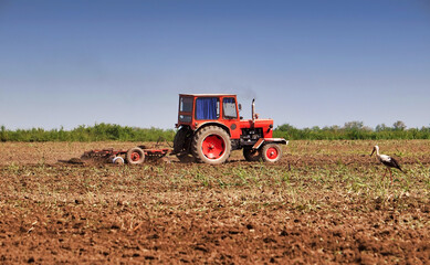 Obraz premium Tractor working farm land with disc harrow