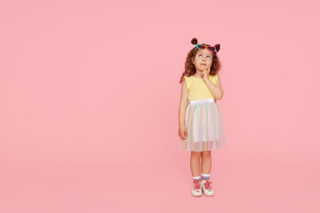 Portrait of surprised cute little toddler girl  in sunglasses over pink background.  Child model have fun and jump. Advertising childrens products