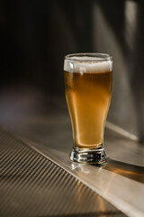 one full beer glass white foam on the bar stand. High quality photo