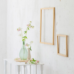 flowers in vase and wooden frames on white interior