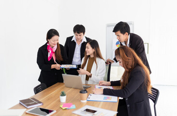 blurred asian female officer teaching about organization business profits to her teams with laptop, they discussion about performance and result, innovation and development, happiness workplace
