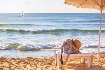 Coastal landscape - straw hat and bag on a deck chair on the background of the sea. Beach holiday...