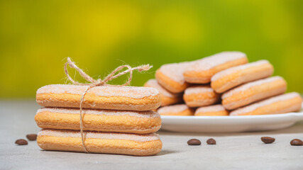Traditional italian savoiardi biscuits or ladyfingers cookies on a plate and in a stack, tied with a rope, selective focus