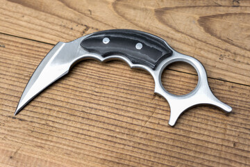 Eagle claw or karambit knife on old wooden background.