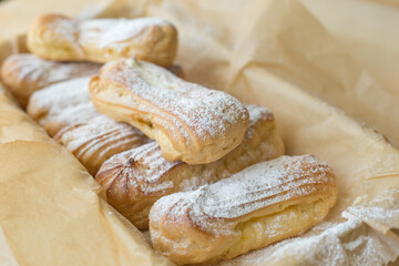 Homemade eclairs on parchment paper ready to eat.
