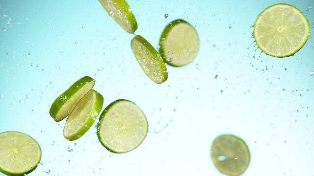 Super slow motion of lime pieces collision with water splashes, white background. Filmed on high speed cinema camera, 1000 fps.