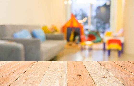 empty wooden table and blurred image of indoor play zone for children