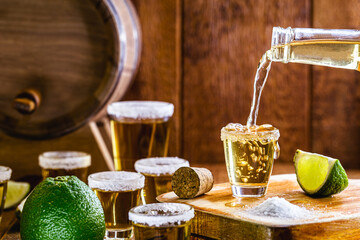 tequila bottle filling glass of drink. Typical mexican drink being served.