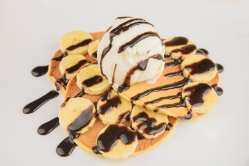 Ice cream with pancakes and banana slices in chocolate sauce