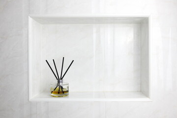 luxury glass aroma reed diffuser bottle with yellow and pink oil are displayed in the nice white toilet bahtroom