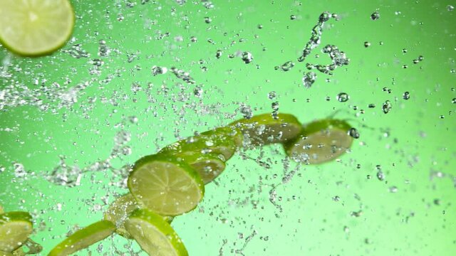 Super slow motion of lime pieces collision with water splashes, green background. Filmed on high speed cinema camera, 1000 fps.