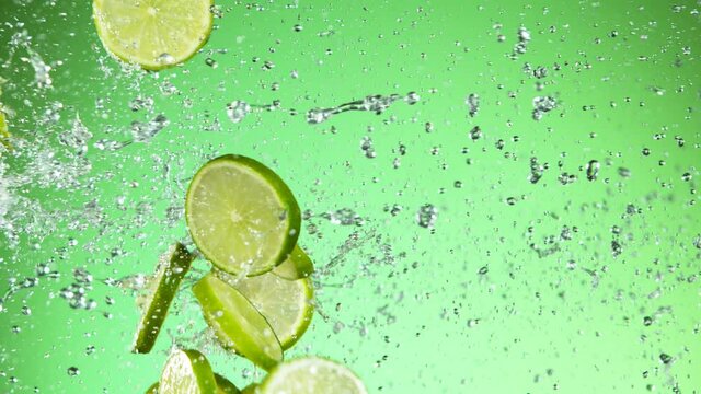 Super slow motion of lime pieces collision with water splashes, green background. Filmed on high speed cinema camera, 1000 fps.