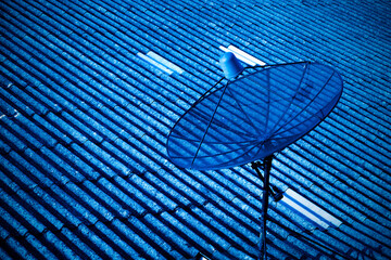 satellite dish receiver on tile roof with blue tone effect.