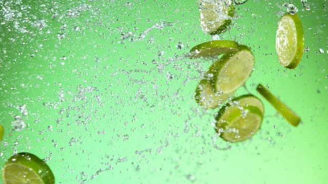 Super slow motion of lime pieces collision with water splashes, green background. Filmed on high speed cinema camera, 1000 fps.