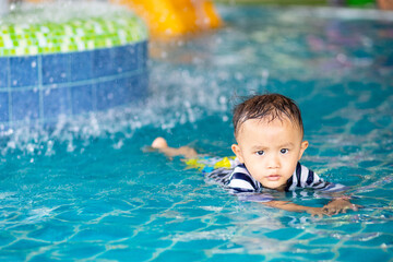 Fototapeta na wymiar Little adorable boy in swimming suit enjoying swimming in the pool