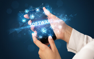 Female hand holding smartphone with SOFTWARE inscription, modern technology concept