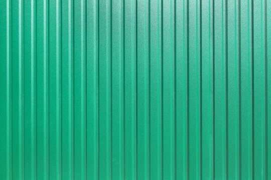 galvanized iron fence with corrugated vertical stripes closeup of the texture of the top coat of a green sheet top view, nobody.