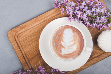 Obraz na płótnie Canvas Lilac, coffee with latte art on gray wooden table. Romantic morning. Flat lay